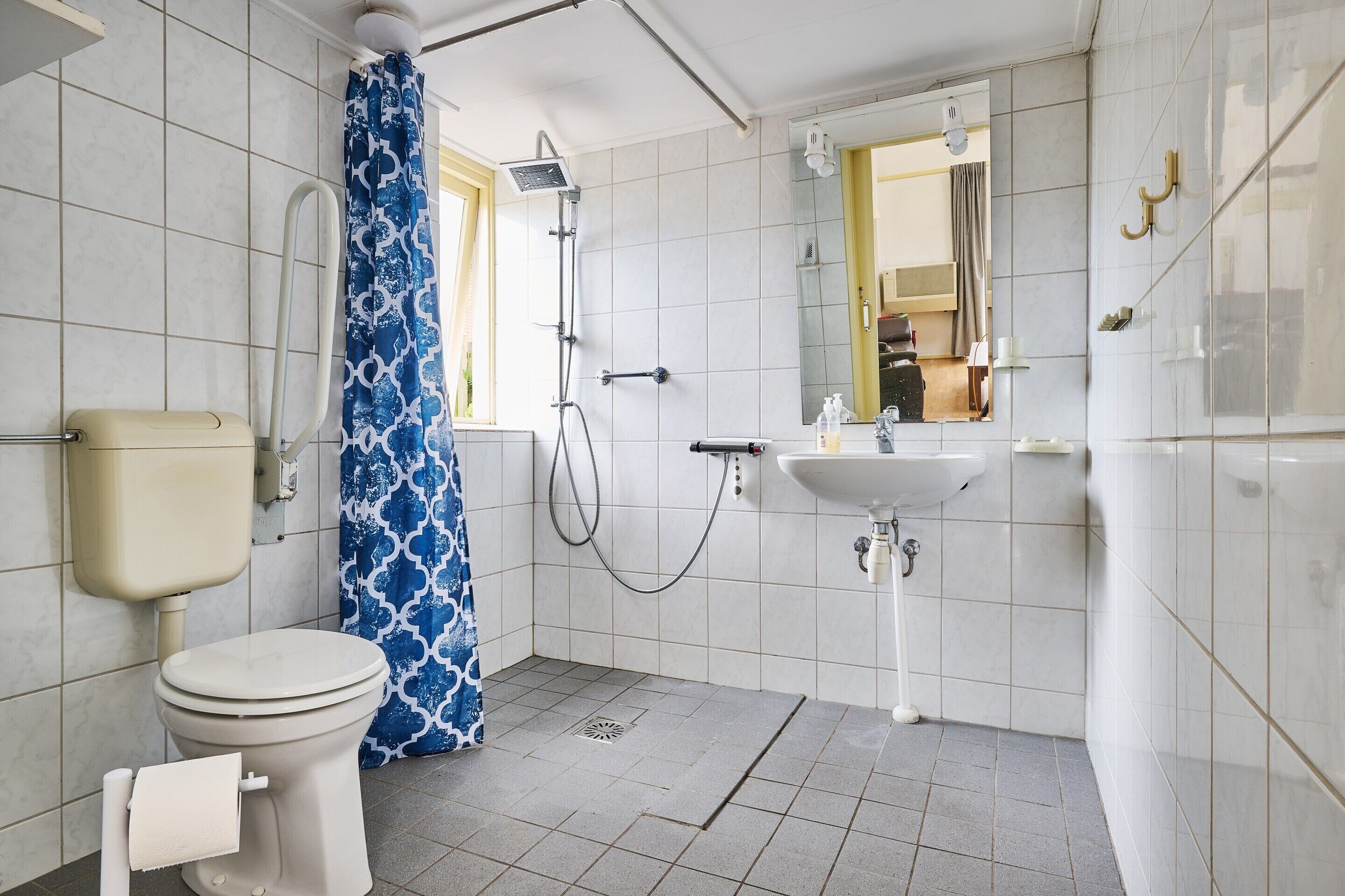 A bathroom with a toilet, shower, sink, and a mirror.