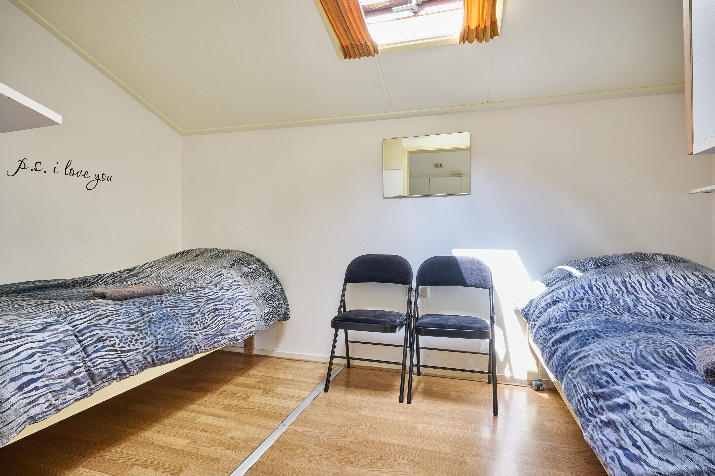 A bedroom with two beds, a mirror, and a wall with a decorative phrase.
