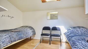 A bedroom with two beds, a mirror, and a wall with a decorative phrase.