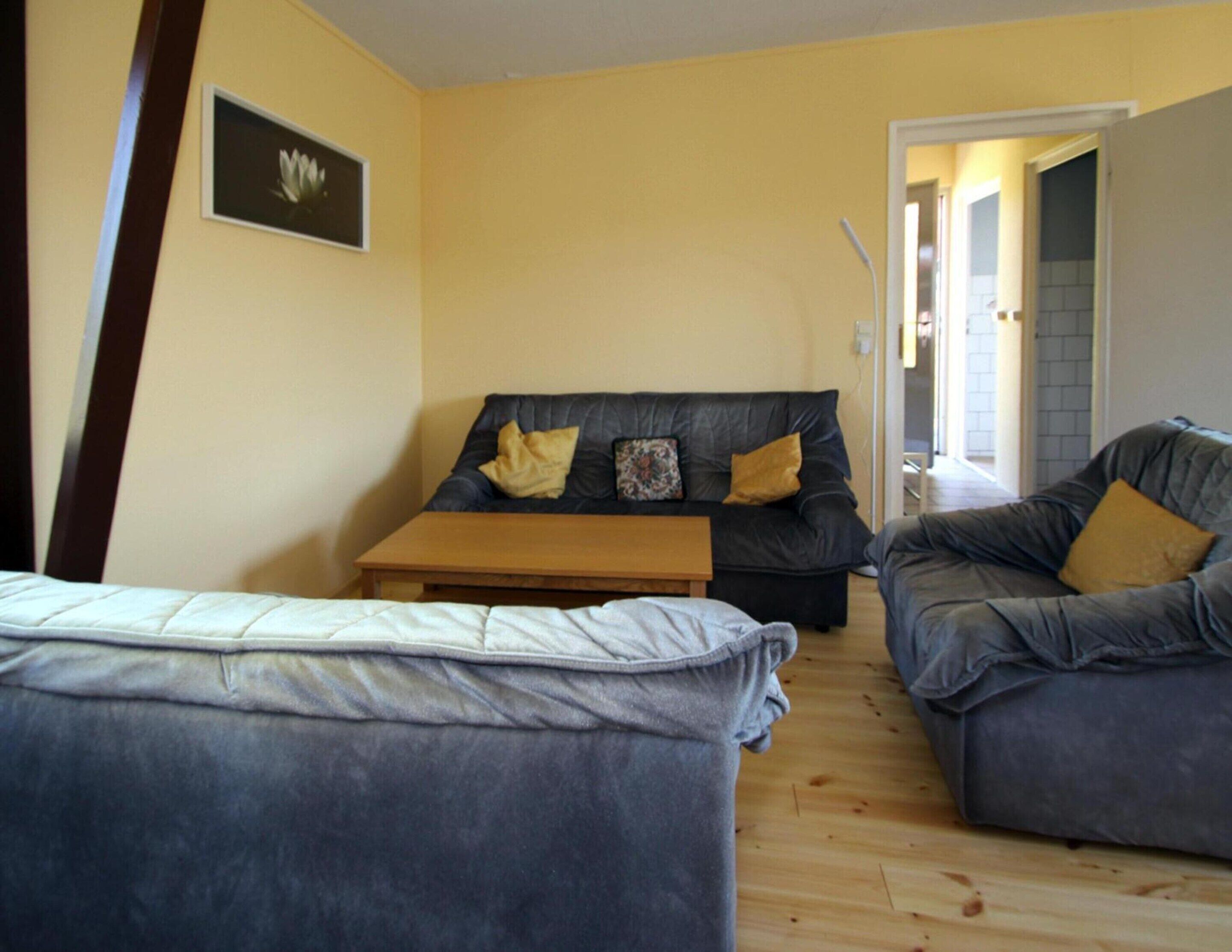 A living room with a sofa, a coffee table, and a bed.