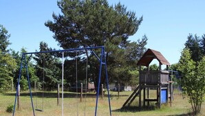A playground with a swing set and a wooden playhouse. - Ferienhaus am Oase am Vilzsee (Mirow)