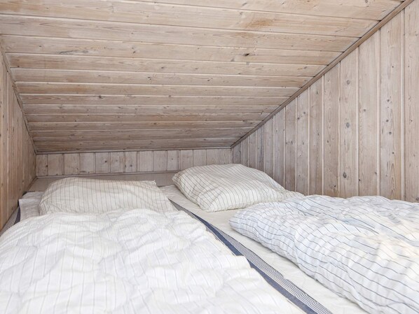 A small, single-occupancy room with a sloped ceiling and wooden walls.