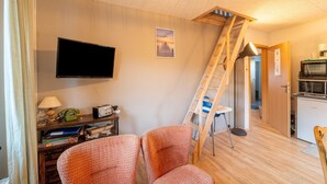 A cozy room with a television, a ladder, a desk with a lamp, and a chair. - Cosy Holiday Home Yalet in Brilon-wald (Brilon)