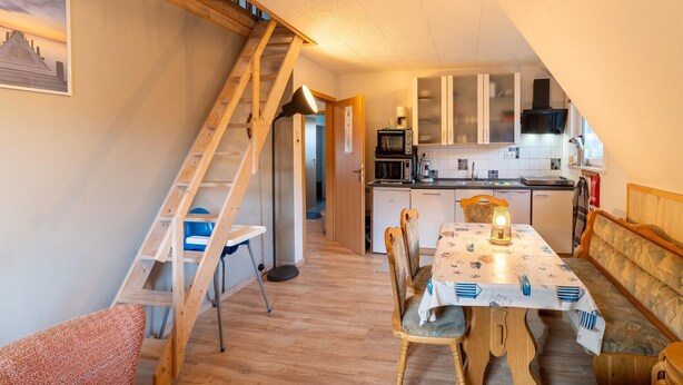 A cozy kitchen with wooden cabinets, a dining table with chairs, and a staircase leading to an upper level. - Cosy Holiday Home Yalet in Brilon-wald (Brilon)