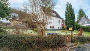 A white house with a sloped roof, a visible garden, and a wooden fence. - Cosy Holiday Home Yalet in Brilon-wald (Brilon)