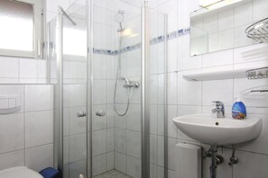 A bathroom with a glass-enclosed shower, a white sink, and a mirror above it. - Inviting log House With 2 Terraces and Cozy Fireplace in Damp (Damp)