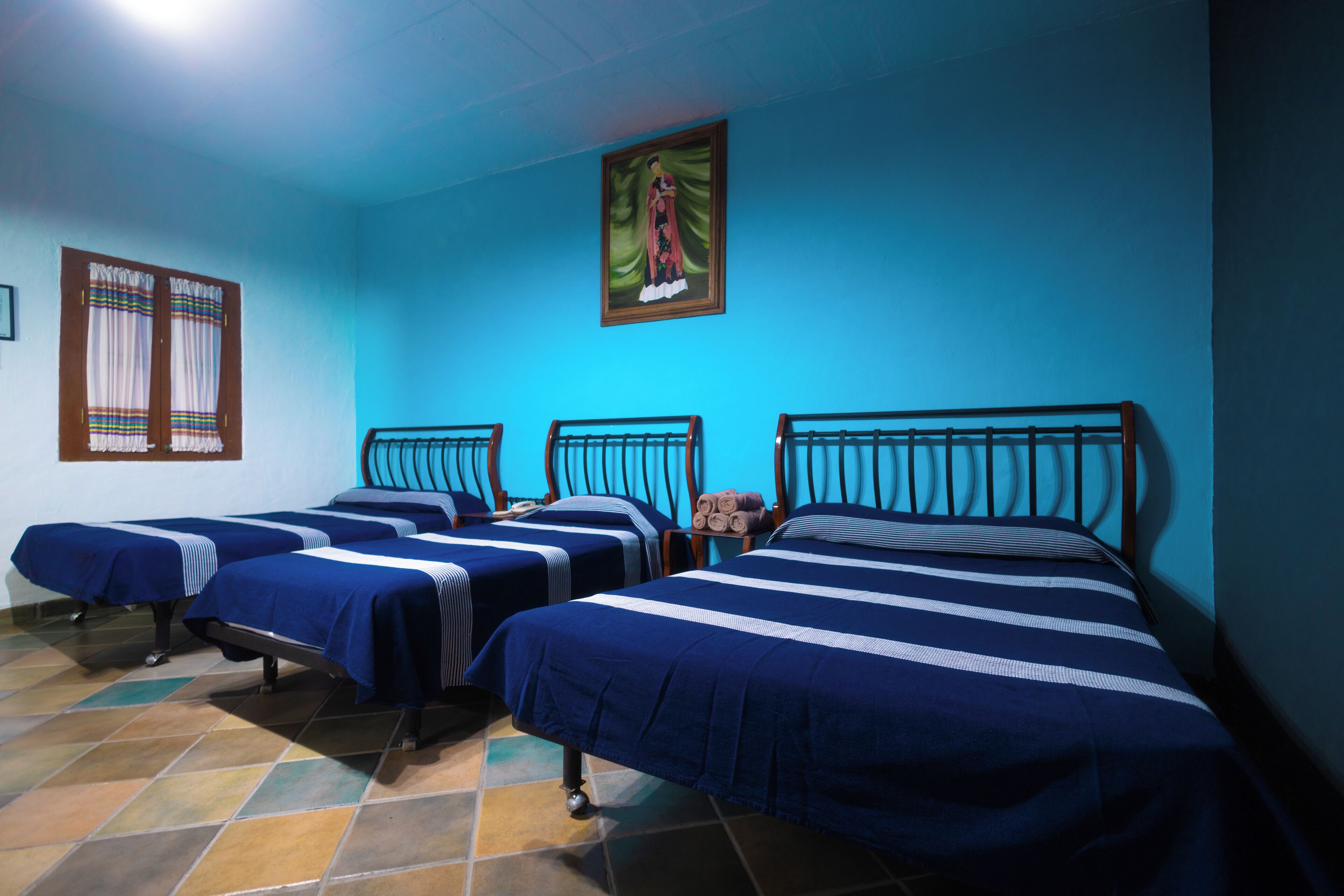 A room with four beds, each with blue bedding and wooden headboards.