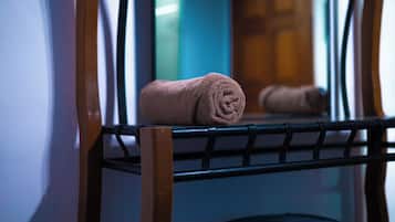 Una toalla doblada con cuidado sobre un tendedero metálico en una habitación con una puerta de madera y una ventana con persianas.