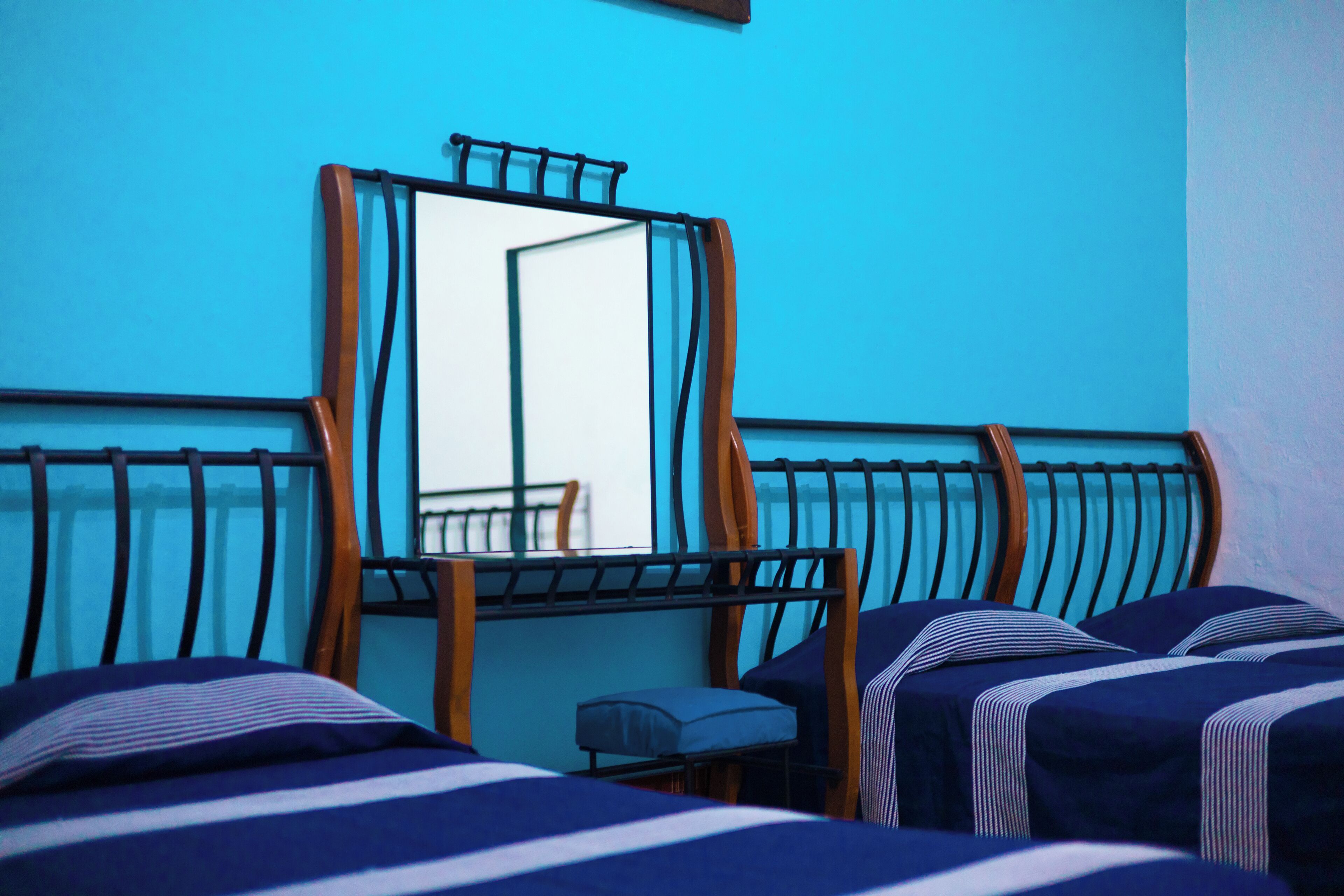 Ein Zimmer mit zwei Betten, einer Bank und einem großen Spiegel.