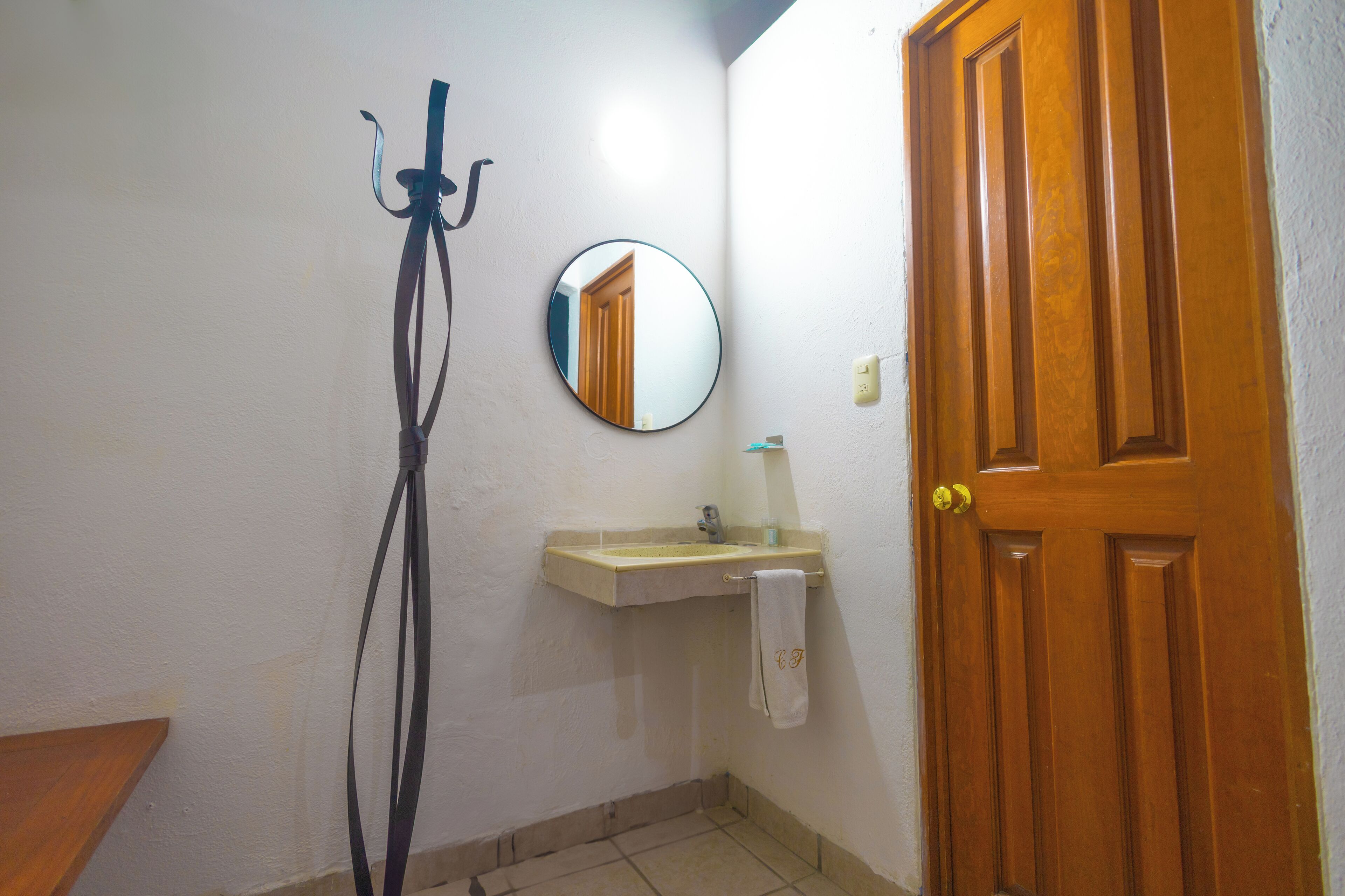 A bathroom with a wooden door, a mirror, a sink, and a towel hanging on the wall.