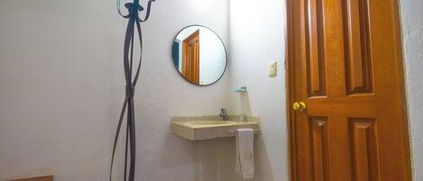 A bathroom with a wooden door, a mirror, a sink, and a towel hanging on the wall.