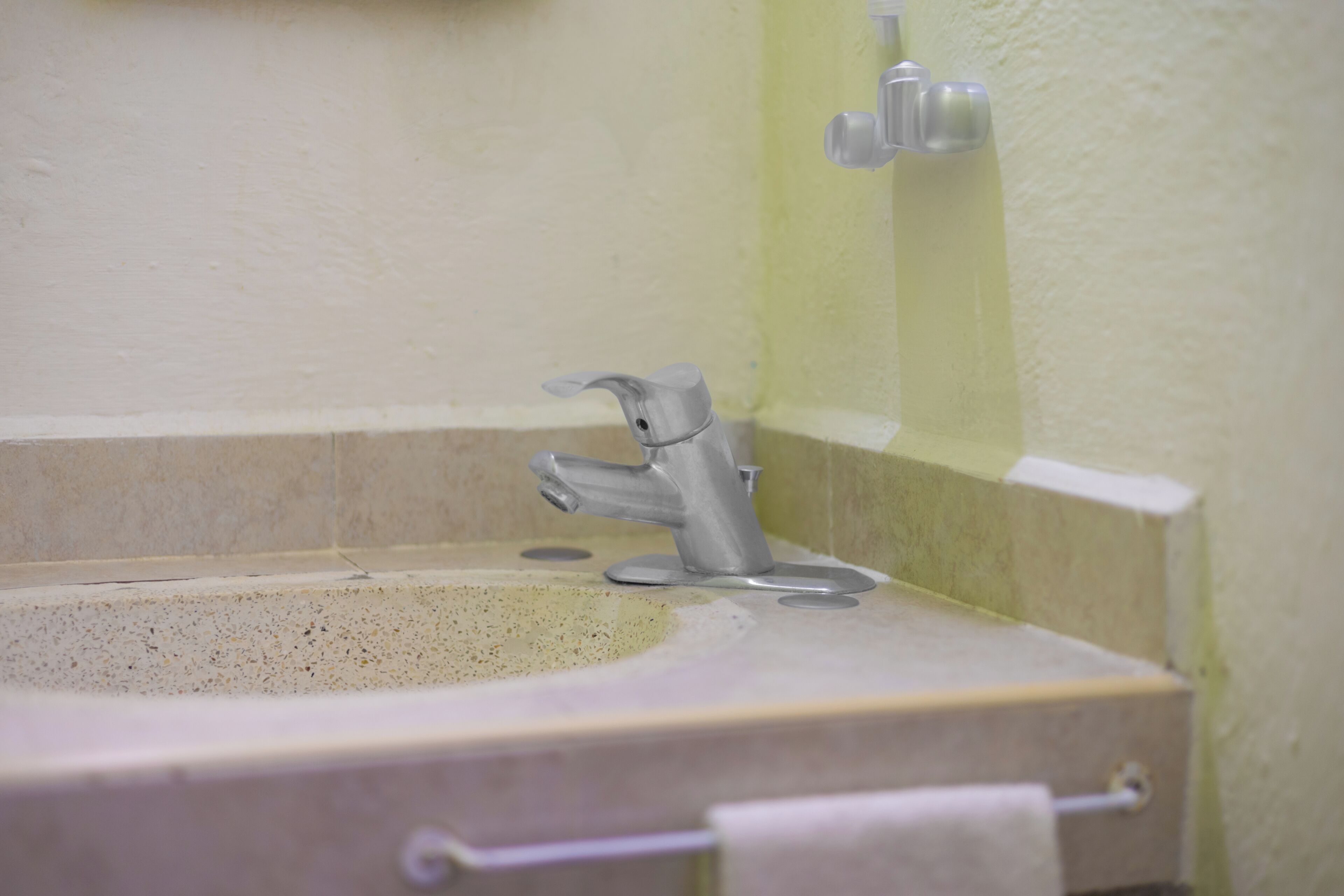 A bathroom sink with a single faucet and a towel hanging on a hook.