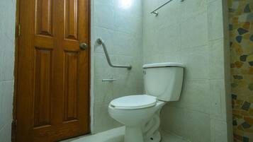 Un bagno con un water bianco, una porta in legno e una parete piastrellata.