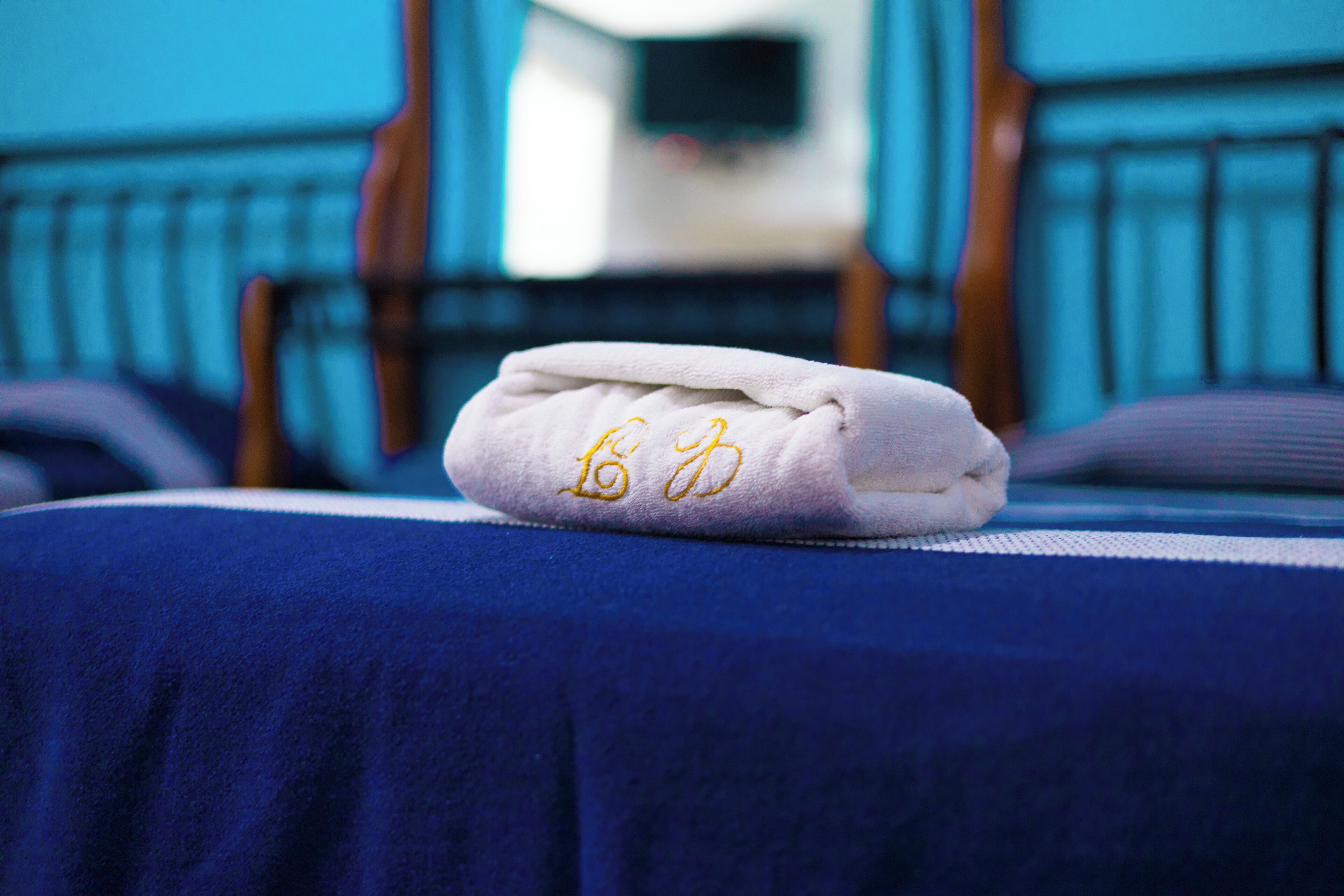 A neatly folded towel with embroidered text on a bed with a blue cover.