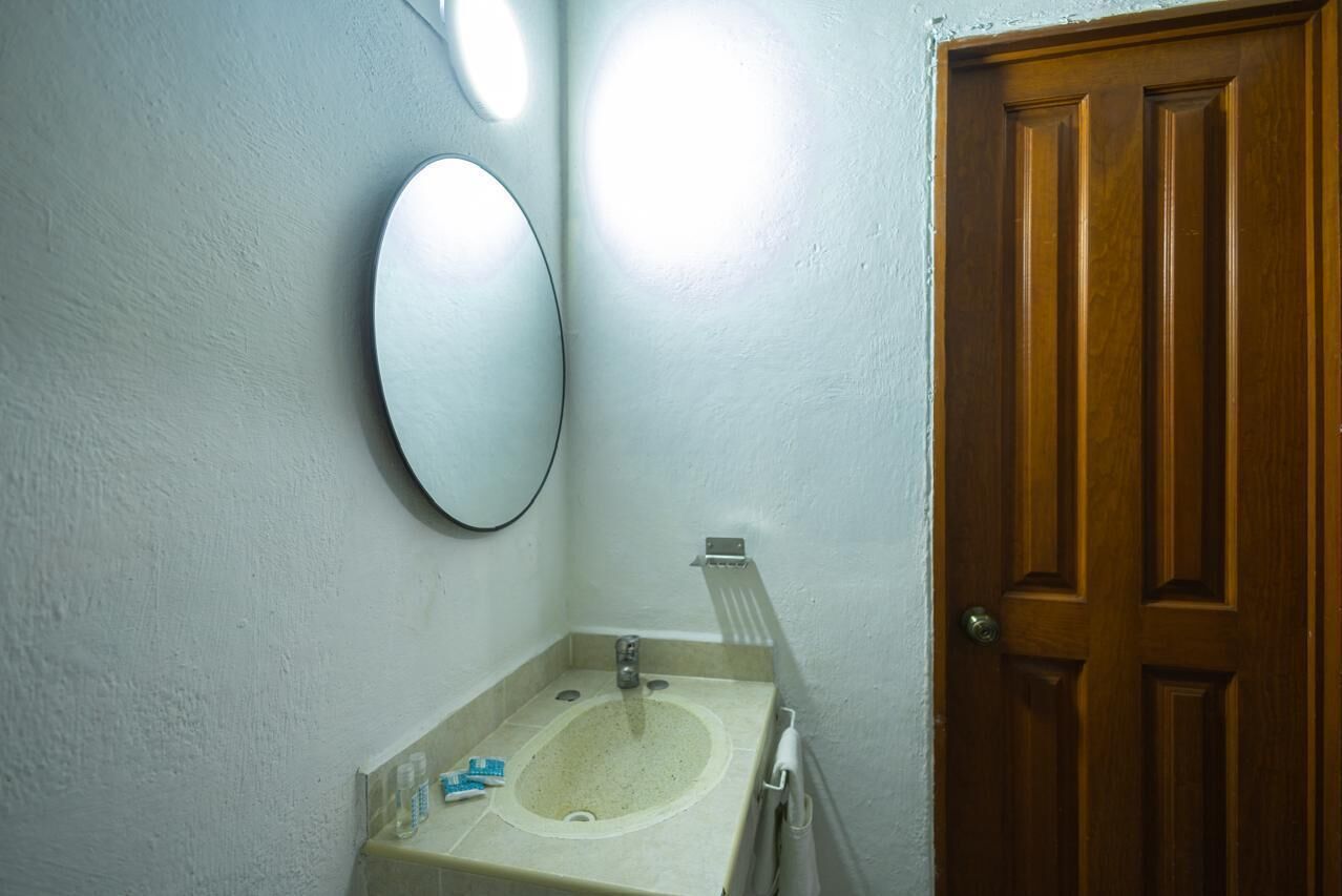 Une salle de bain avec un lavabo, un miroir et une porte en bois.