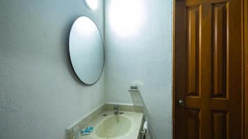 Une salle de bain avec un lavabo, un miroir et une porte en bois.