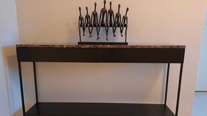 Une table en bois foncé, dotée d’une étagère et ornée d’une sculpture métallique décorative sur le dessus.