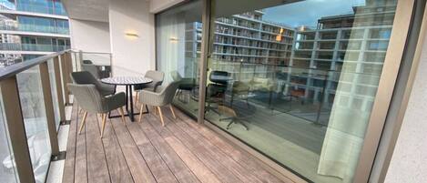 A balcony with wooden flooring, a round table, and four chairs.