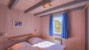 Un dormitorio acogedor de madera con cama, ventana con cortinas y un cuadro en la pared.
