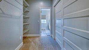 A narrow hallway with a carpeted floor, a metal shelving unit, and a garage door. - -:- Cowboy Casa -:- Modern New Construction - 3BR+  (Cody)