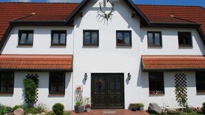 A two-story building with a symmetrical facade, a central entrance with a black door, and a decorative deer head above the door. - Studio in Dargun With Pool Near Lake Kummerow (Dargun)