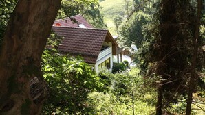 Ein Haus mit rotem Dach in einem bewaldeten Tal.
