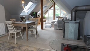 Ein großzügiges Loft mit Essbereich, Sitzgelegenheiten und einem Kaminofen.