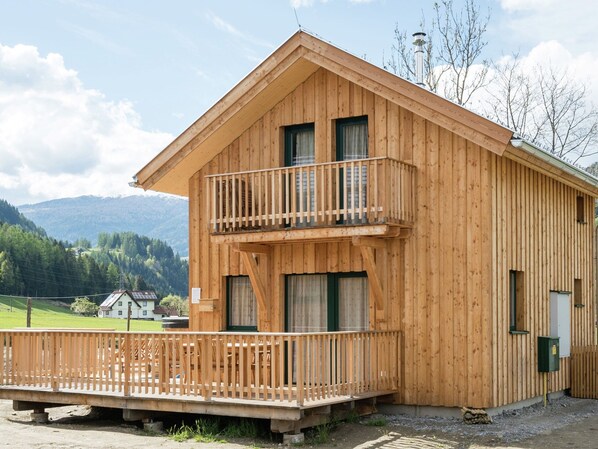 A wooden chalet with a balcony, a front porch, and a view of a mountainous landscape. - Amazing Chalet With hot tub (Sankt Georgen am Kreischberg)
