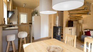 A modern kitchen with wooden accents, a dining area with a wooden table, and a cozy living space with a fireplace. - Amazing Chalet With hot tub (Sankt Georgen am Kreischberg)