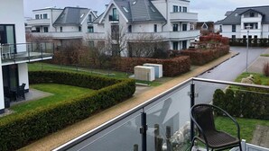 A residential area with modern houses, a paved pathway, and a balcony with a chair. - Appartementhaus Calmsailing, Borgerende (Boergerende-Rethwisch)