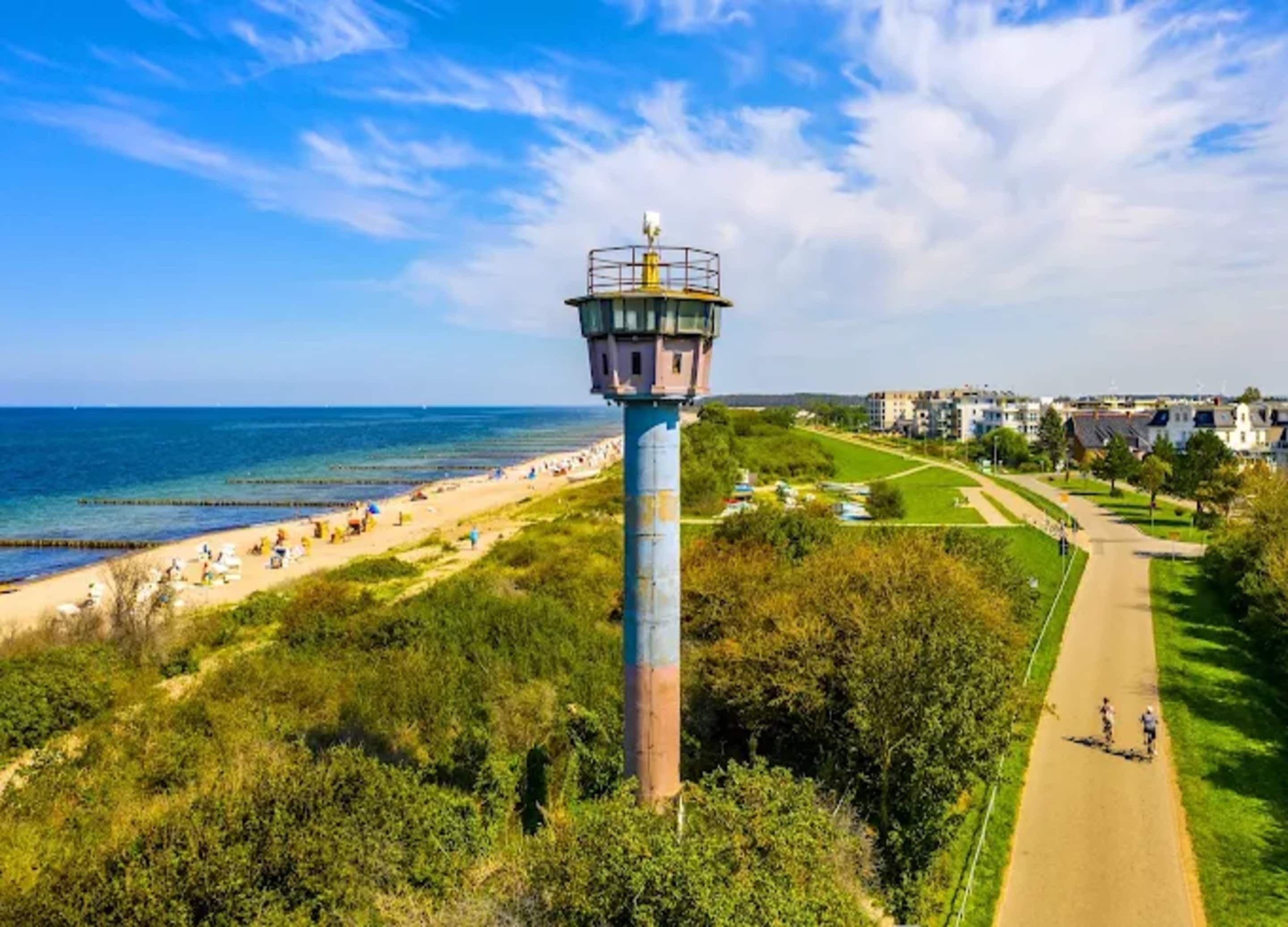 Vista costeira com farol, praia e área residencial.