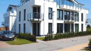 A modern two-story building with balconies, a car parked in front, and a well-maintained lawn. - Appartementhaus Calmsailing, Borgerende (Boergerende-Rethwisch)