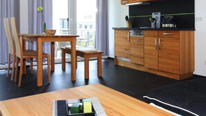 A modern kitchen with wooden cabinets and a black countertop. - Appartementhaus Calmsailing, Borgerende (Boergerende-Rethwisch)