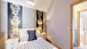 A bedroom with a bed, nightstands, and wall art.