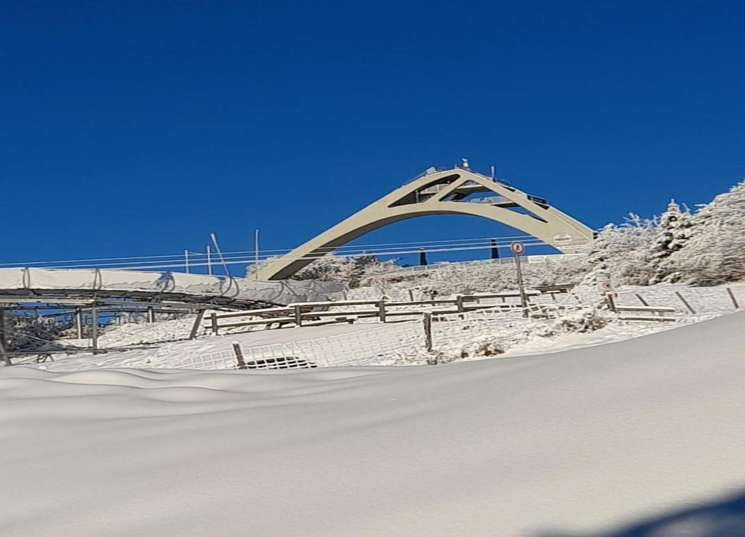 Un paysage enneigé avec un grand pont en arc et une clôture en bois.