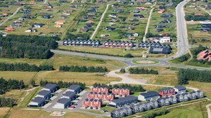 Vue aérienne d’une zone résidentielle côtière, avec des maisons, des routes et une plage.