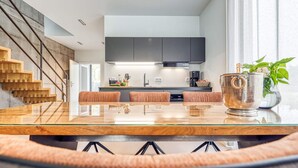 Una cocina moderna con una isla central, electrodomésticos integrados y una escalera.