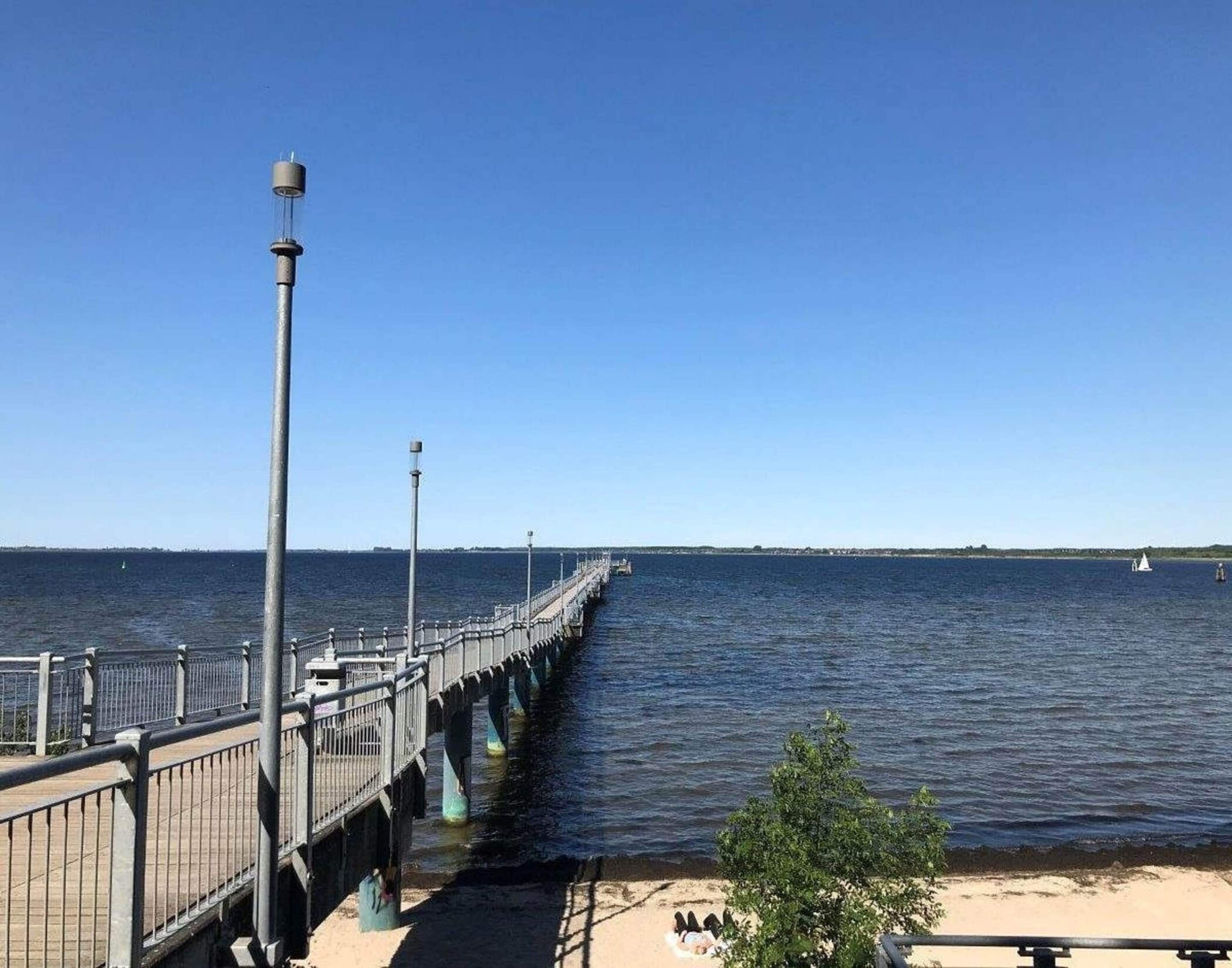 A pier extending into calm waters with a clear sky.