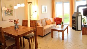 A living room with a wooden dining table, sofa, and a fireplace. - Ferienwohnung im Ferienpark Mueritz (Rechlin)