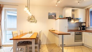A compact kitchen with a wooden table, chairs, a built-in oven, and a stove. - Exquisite Ferienwohnung in Rechlin (Rechlin)