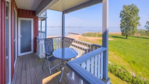A wooden deck with a table and chairs, overlooking a grassy area and a body of water. - Exquisite Ferienwohnung in Rechlin (Rechlin)
