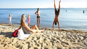 A beach scene with people relaxing and one person doing a handstand. - Exklusives Appartement in Rechlin (Rechlin)