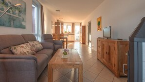 A modern living room with a sofa, coffee table, and wooden cabinet. - Exklusives Appartement in Rechlin (Rechlin)