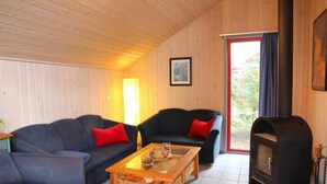 A cozy living room with a sofa set, a coffee table, a fireplace, and a door leading outside. - Skandinavisches Ferienhaus in Mirow (Mirow)
