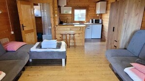 A cozy cabin interior with a living area, a kitchenette, and a bathroom. - Cottage in Dziwnowek Near Baltic Beach (Dziwnów)