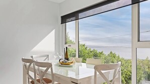 A dining area with a table and chairs, a bottle of wine, and a banana on the table.