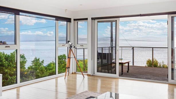 A spacious room with large windows offering a view of the sea.