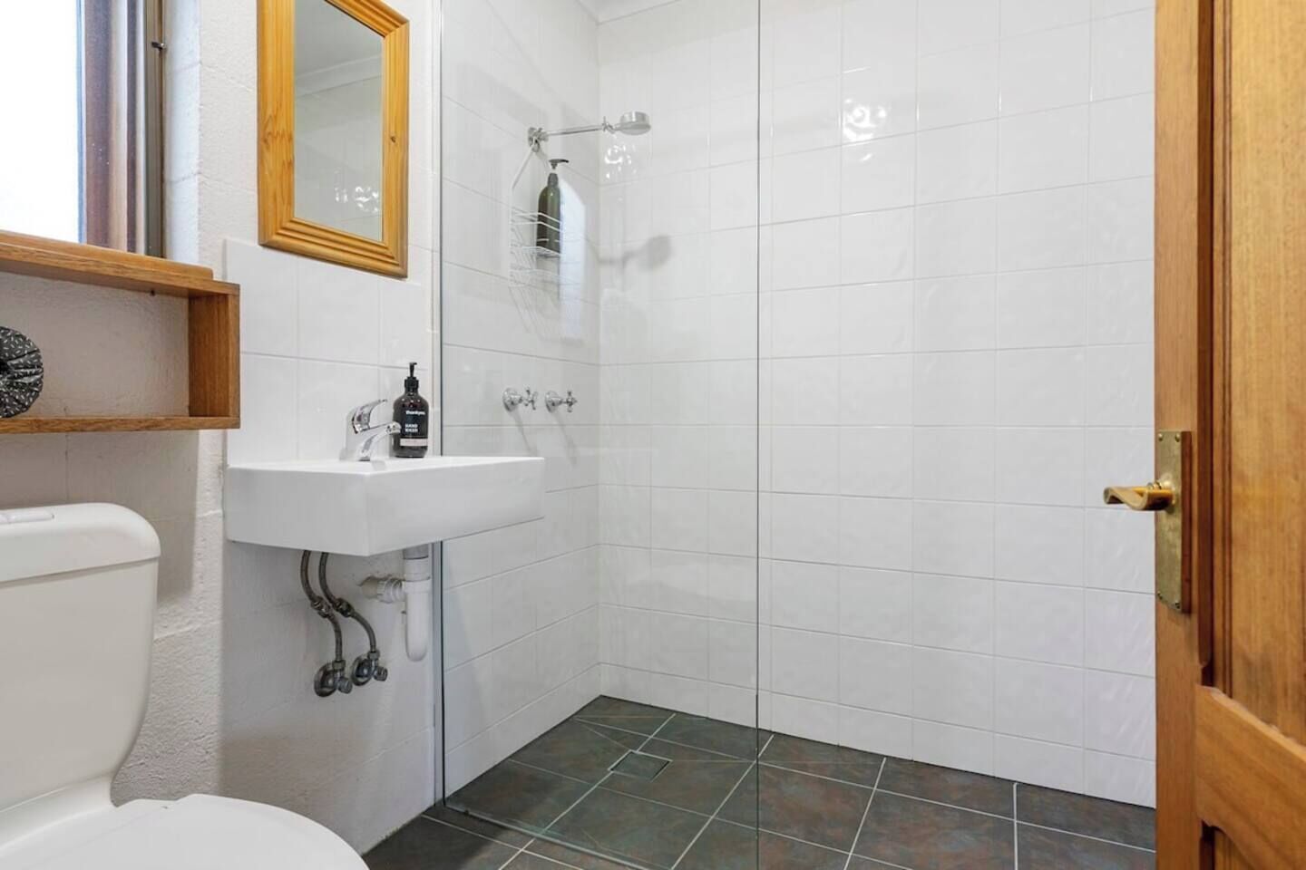 A bathroom with a white sink, a mirror, a shower, and a toilet.
