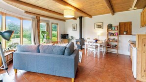 Una sala de estar acogedora con sofá, una mesa de comedor y una cocina con armarios de madera y chimenea.