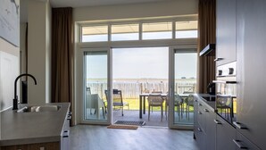 Una cocina moderna con un amplio ventanal corredero que da a un patio exterior con vistas al agua.